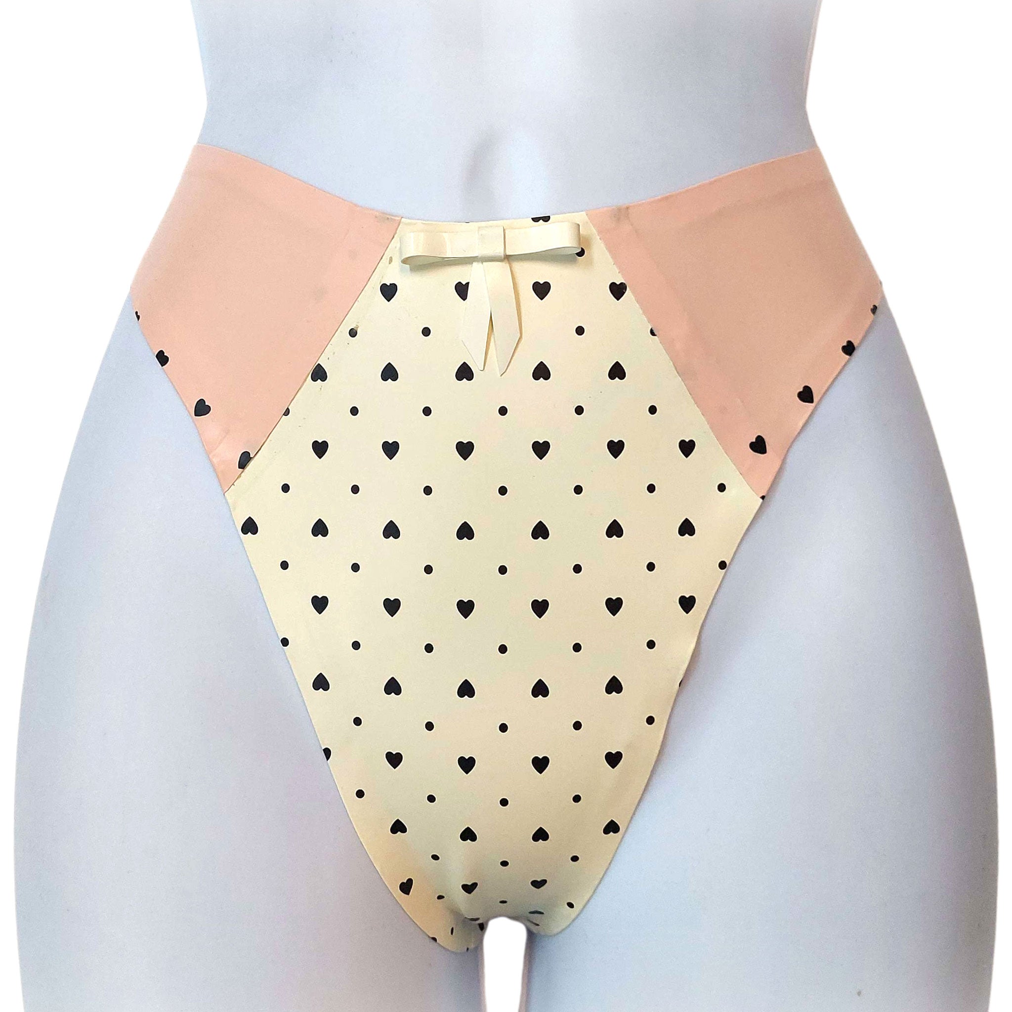 Latex rubber printed-latex apparel intimates lingerie latex-lingerie panties panty latex-panties thong g-string pullon pull-on printed-panels polka-dots heart-shaped polkadot-pattern latex-bow sophisticated sensual luxurious quirky fetish fashion alt-fashion alternative retro-fashion rockabilly 50s-retro 40s-retro kink kinky kinkwear costume cosplay female femme feminine women white warm-white pink baby-pink