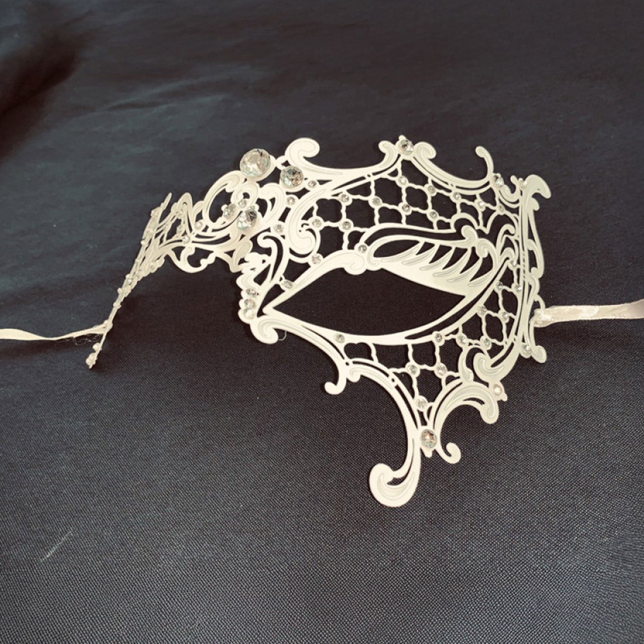 Metallic metalwork semi-flexible semi-malleable laser-cut rhinestones gems accessories mask eye-mask filigree-mask asymmetrical one-eye tie-on satin-ribbon elegant elegance sparkling luxury luxurious delicate graceful refined costumes cosplay Halloween masquerade masquerade-ball party bridal formal-ball winter winter-themed unisex white clear