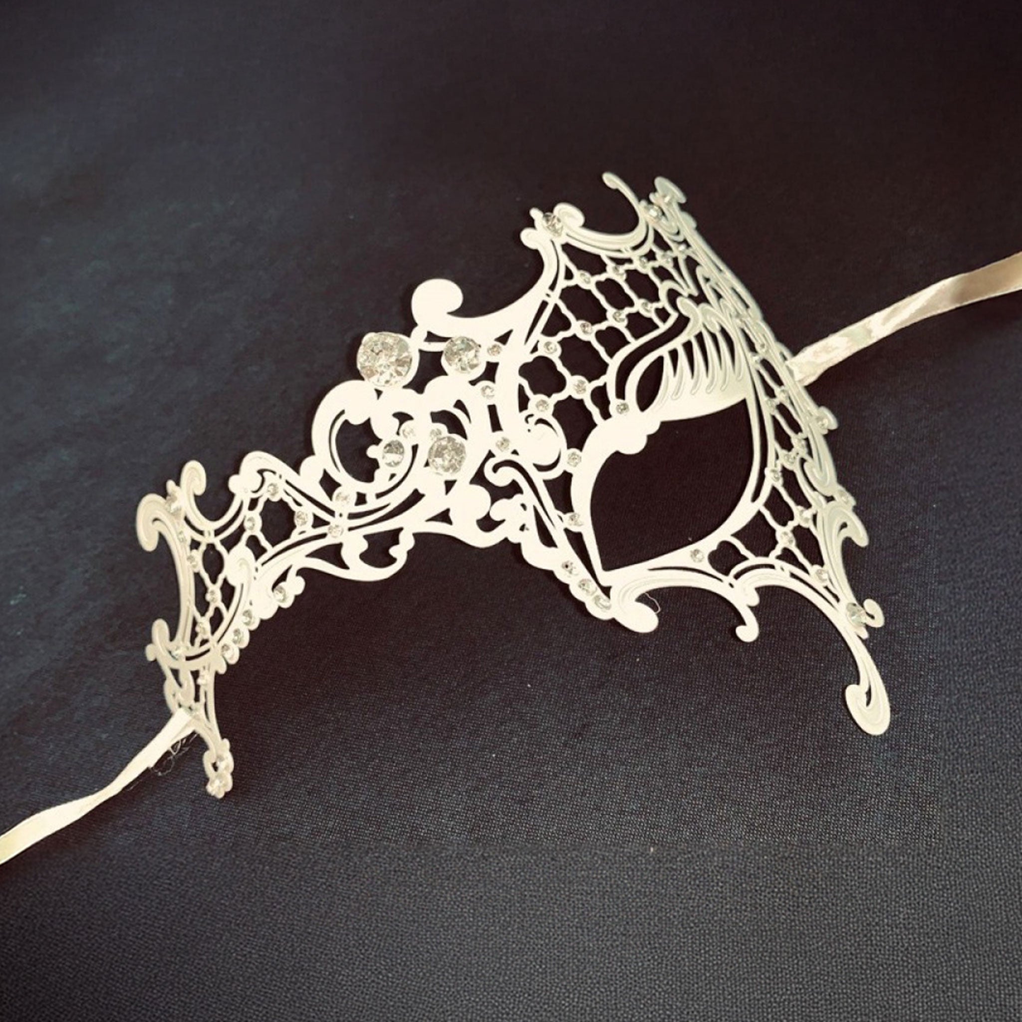 Metallic metalwork semi-flexible semi-malleable laser-cut rhinestones gems accessories mask eye-mask filigree-mask asymmetrical one-eye tie-on satin-ribbon elegant elegance sparkling luxury luxurious delicate graceful refined costumes cosplay Halloween masquerade masquerade-ball party bridal formal-ball winter winter-themed unisex white clear